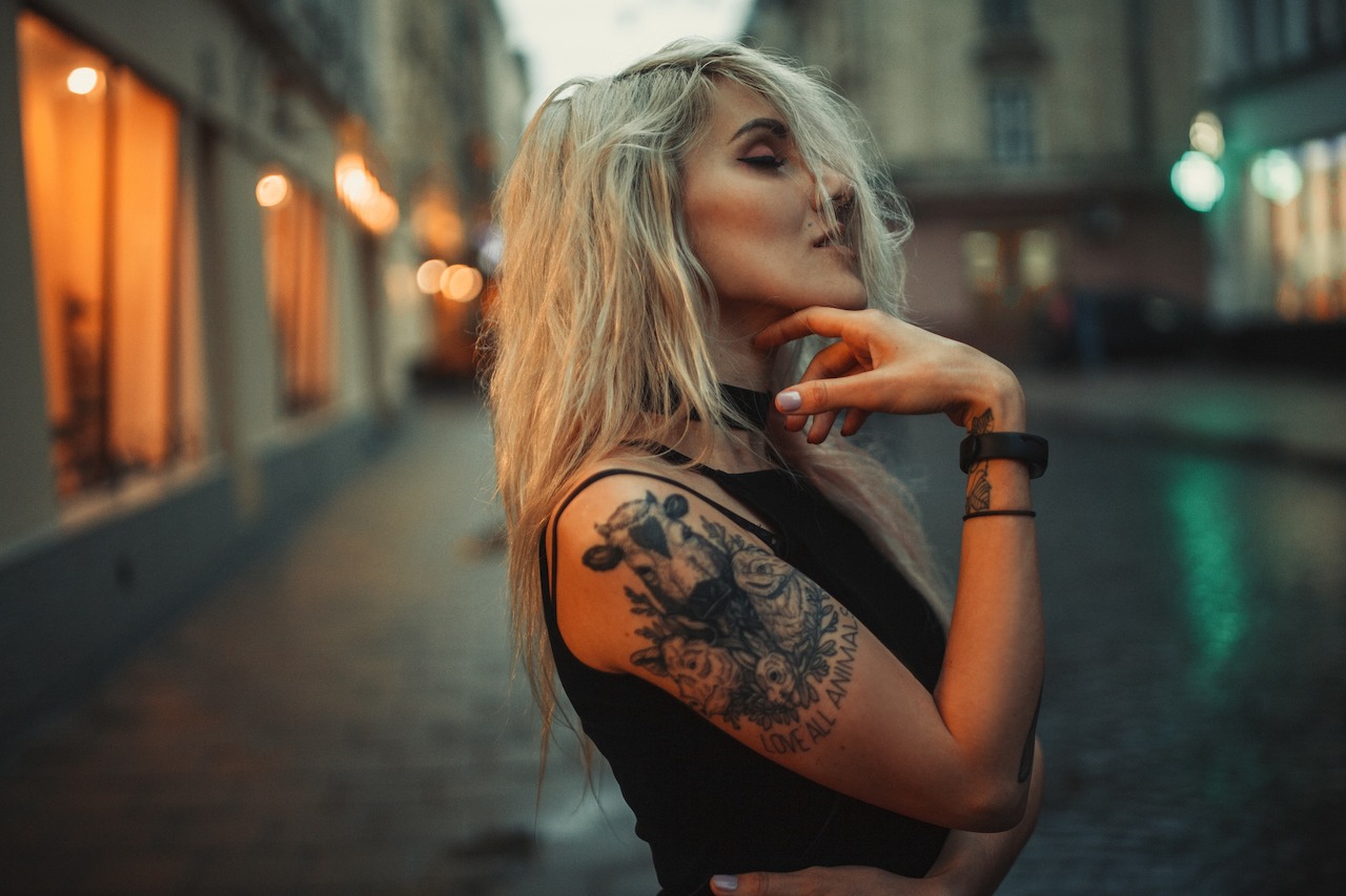 Young,woman,portrait,with,tattoo,on,shoulder,standing,on,city